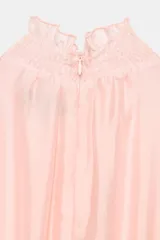 Mono largo con parte superior de blusa rosa de manga larga, cuello alto fruncido y puños con volantes. La parte inferior es un pantalón negro de pernera ancha con bolsillos delanteros y un cinturón negro con hebilla dorada.