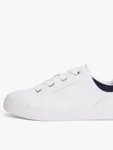 Zapatillas de tenis minimalistas Tommy Hilfiger, confeccionadas en piel napa blanca con suela gruesa tipo cupsole. Presentan un diseño de corte bajo con cordones, detalle de panel azul marino en el talón y logo metálico de la marca en el lateral.
