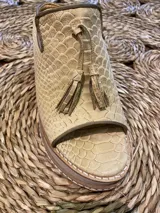 Sandalia de cuero color beige con textura de piel de serpiente, con puntera abierta y detalle de flecos.
