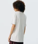 Remera oversized de algodón color gris claro, con cuello redondo y mangas cortas. Presenta una estampa frontal de mariposa marmolada en tonos tierra con pequeños detalles de strass.