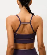Top deportivo de microfibra en color violeta con detalles de friso en tono arena. Presenta un diseño de escote redondo, breteles finos y una banda inferior elástica que proporciona mayor sujeción. Incluye copas removibles para mayor comodidad.