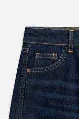 Jeans de tiro medio color azul oscuro, con cinco bolsillos, cierre de cremallera y botón. Presenta una silueta curvada, más ancha en el muslo y la rodilla, y un bajo con vuelta.