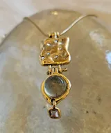 Collar dorado con cadena fina y dije con forma irregular con incrustaciones y dije colgante con piedra prehnita redonda y dije cuadrado pequeño. 