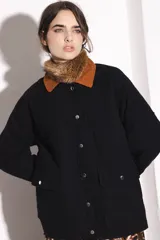 Campera negra con cuello y puños de pana marrón, cierre frontal con botones a presión y bolsillos delanteros con solapa. Diseño acolchado con costuras en forma de rombos.