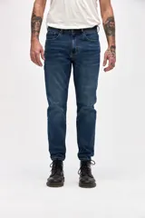Jean de corte slim, entallado en cadera y muslos con ajuste gradual desde la rodilla hasta el tobillo. Presenta un lavado azul oscuro clásico con costuras reforzadas y cierre frontal con botón y cremallera.