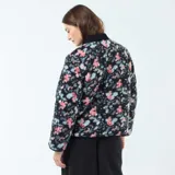 Chaqueta corta con estampado floral en tonos rosa y celeste sobre fondo negro. Tiene cuello mao y cierre frontal con botones a presión.