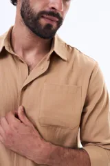 Camisa de manga larga color verde oliva, con cuello clásico, cierre frontal con botones y un bolsillo en el pecho.