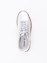 Zapatilla urbana de estilo retro, color plateado metalizado, con cordones al tono y suela de goma color marrón.
