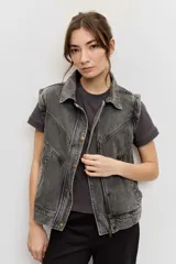 Chaleco de denim color gris deslavado, con cuello camisero, cierre frontal con botones metálicos y costuras decorativas.