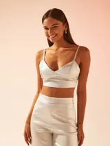 Top corto tipo bralette de tela satinada brillante, con escote en V y breteles finos ajustables.