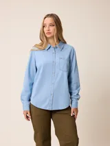 Camisa de jean de manga larga con cuello clásico, cierre frontal con botones y bolsillo en el pecho.