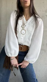 Camisa blanca de manga larga abullonada, con delicados bordados frontales y cierre con botones.