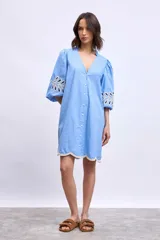 Vestido celeste con escote en V, mangas 3/4 abullonadas con bordado calado y ruedo con detalle de puntilla.