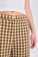 Pantalón de corte recto y tiro medio con estampado de cuadros vichy en tonos verde y beige. Cuenta con bolsillos laterales y cierre frontal.