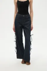 Pantalon de jean azul oscuro de corte ancho y tiro bajo, con detalle de aberturas laterales ajustables mediante lazos.