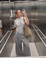Remera gris de corte regular con estampa central pequeña que presenta letras coloridas con efecto inflado sobre un fondo de nubes.