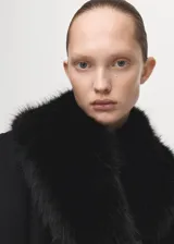 Abrigo largo negro de lana italiana con cuello de pelo sintético desmontable y cinturón tipo batín.