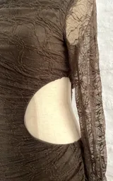 Vestido corto marrón con textura arrugada, cuello alto asimétrico y una manga larga. Presenta un corte en la cintura.