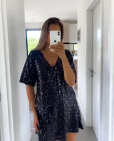 Túnica corta de color negro, completamente cubierta de lentejuelas brillantes. Presenta un escote en V, mangas cortas holgadas y un corte recto y cómodo.