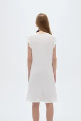 Vestido midi de poliéster color blanco, de corte recto y escote redondo a la base, con mangas cortas abuchonadas con volados y detalles de volados en el ruedo.