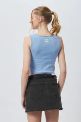 Musculosa corta negra sin mangas, de corte asimétrico frontal y ceñida al cuerpo.