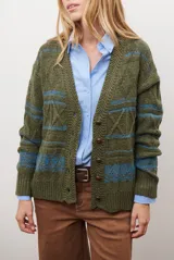 Sacon de tejido de punto grueso con diseño de ochos y rayas horizontales en contraste. Presenta cuello en V, cierre frontal con botones oscuros y mangas largas con puños acanalados.