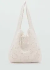 Bolso shopper de crochet en color crudo, con diseño de motivos circulares unidos en tejido artesanal y tiras ajustables con lazo en la parte superior. Cuenta con doble asa de hombro.