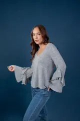 Blusa gris melange de punto tejido fino, con escote en V y mangas largas anchas terminadas en volados.