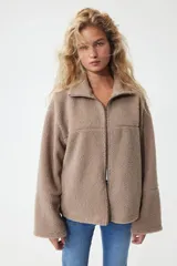 Campera oversized de sherpa con cuello elevado, cierre frontal y mangas largas amplias de hombros caídos.