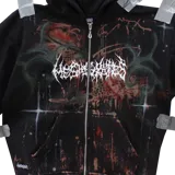 Canguro negro con cierre frontal, capucha y bolsillos tipo canguro. Presenta un diseño personalizado con serigrafía, pintura a mano con aerógrafo y efecto bleach en tonos marrones y verdes, además de un estampado gráfico frontal estilo gótico.