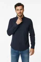 Camisa de algodón azul marino, de corte recto, con cuello camisero, cierre frontal de botones y un bolsillo en el pecho.