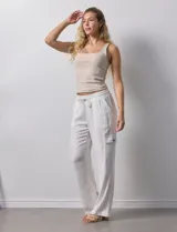 Pantalón cargo de lino a rayas verticales grises y blancas, marca Marissa Olivia. Pretina ancha elastizada con lazo de ajuste, bolsillos inclinados delanteros y bolsillos laterales con botón.