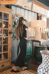 Vestido largo de punto acanalado en color negro, con escote en V, mangas cortas y aberturas laterales en el ruedo.