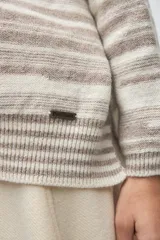 Buzo de tejido de punto con diseño de rayas horizontales en tonos beige y blanco, cuello redondo, hombros caídos y mangas largas.