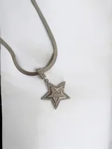 Collar de cadena tipo serpiente con dije de estrella pavé, elaborado en acero quirúrgico con acabado plateado.
