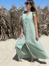 Vestido largo fucsia de lino, con corte recto, breteles anchos con volados y botones frontales. Presenta un tajo lateral.