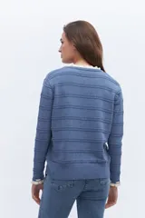 Sweater de punto negro con detalle de calados y lazo en el escote. Tiene ribetes con volados en contraste en el cuello y puños.