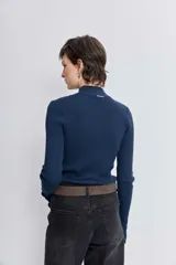 Blusa de punto acanalado en color azul marino, con cuello alto y mangas largas ajustadas.