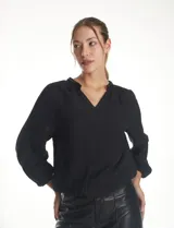 Blusa de satén color verde oscuro, de manga larga abullonada con puños elásticos. Presenta cuello redondo con escote en V y detalles de bordado con mostacillas en el cuello.