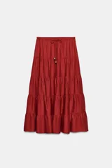 Falda midi color rojo oscuro con diseño de paneles fruncidos, cintura elástica con cordón ajustable y abalorios decorativos.