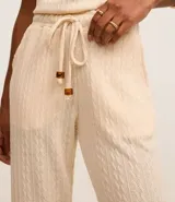 Pantalón zanahoria color crema, con cintura elástica, lazo, bolsillos laterales y superficie texturizada.