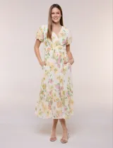 Vestido maxi de gasa color beige con estampado floral en tonos amarillos y rosados, escote en V cruzado, mangas cortas abullonadas y cintura elastizada con nido de abeja.