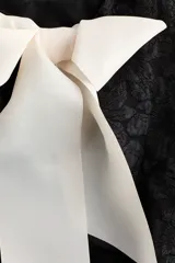 Top sin mangas negro de tejido jacquard con diseño texturizado, escote redondo y corte peplum acampanado.