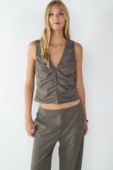 Top sin mangas color gris con rayas diplomáticas blancas, escote en V y detalle drapeado en el frente. Tiene cierre frontal.