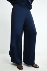 Pantalón de tiro medio confeccionado en tejido satinado con diseño tipo pareo. Presenta pernera recta, falsos bolsillos de vivo en la parte trasera y cierre frontal con botón a presión junto a una cremallera oculta en el lateral.