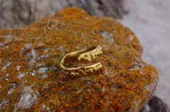 Anillo abierto de diseño orgánico con textura irregular y acabado brillante, realizado artesanalmente en metal.