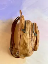 Mochila Lucy de cuero color terra con efecto desgastado, múltiples bolsillos externos con cierre y herrajes de metal envejecido.