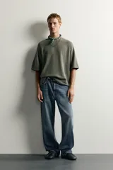 Jeans de denim de algodón en color azul con efecto desgastado, tiro medio y corte recto de ajuste holgado (loose fit). Cuenta con diseño clásico de cinco bolsillos y cierre frontal con cremallera y botón.