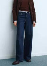 Jeans Annie de tiro bajo y diseño wide leg con perneras anchas, confeccionados en tejido denim de algodón en color azul oscuro. Cuenta con cinco bolsillos, trabillas para cinturón y cierre frontal con botón y cremallera.
