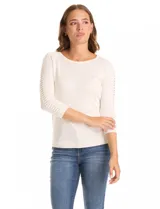 Buzo de tejido fino en color blanco, con cuello redondo y mangas tres cuartos tipo raglán. Presenta un detalle decorativo de tachas metálicas a lo largo de las mangas.